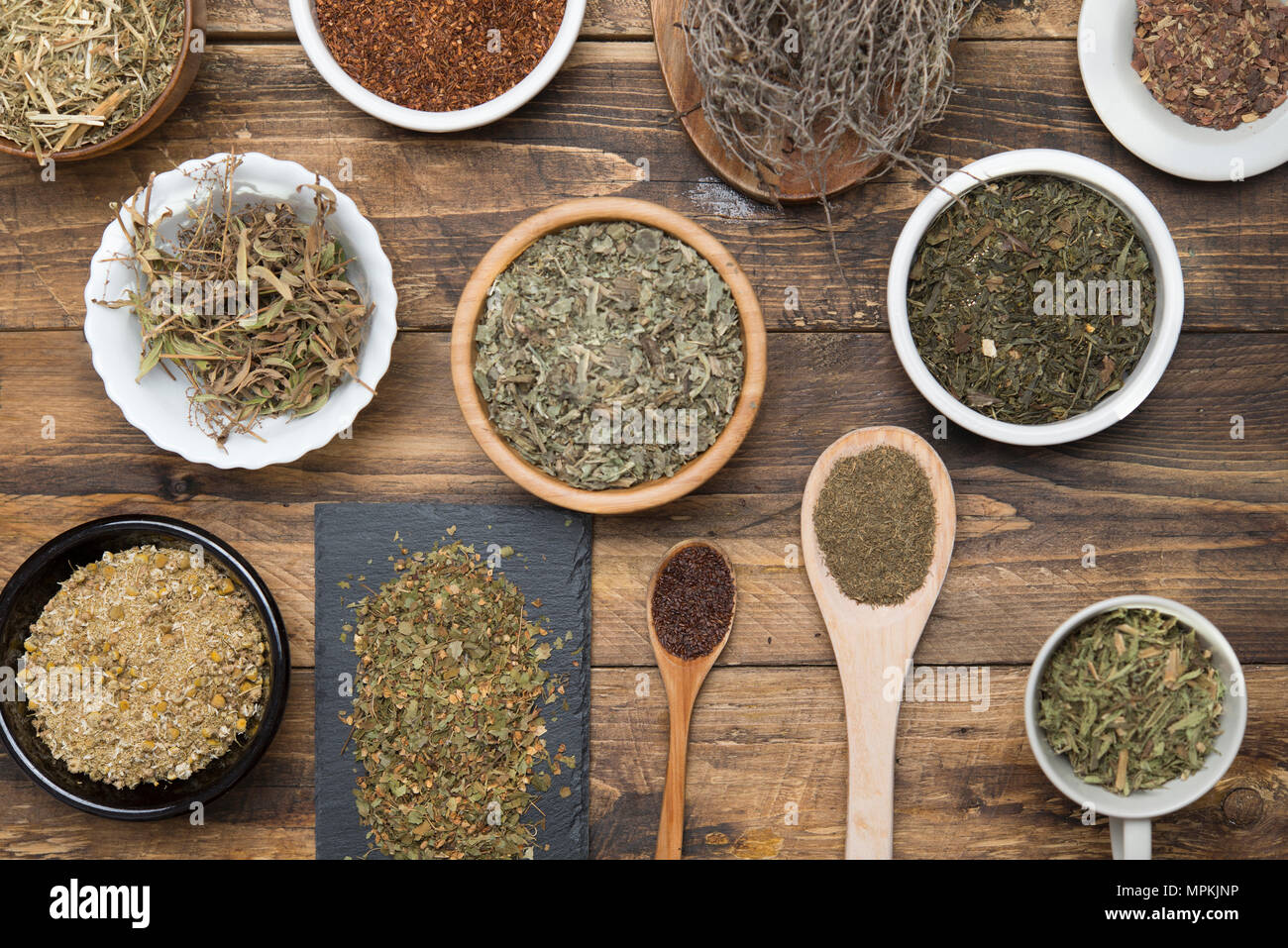 Various herbal infusions on wood, chamimile, mint, rooibos, thyme, green tea, tisane Stock Photo