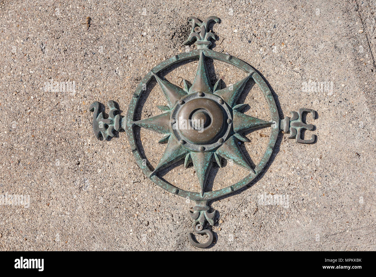 Old wind rose navigational compass symbol attached to concrete sidewalk at the Pass Christian Yacht Club in Pass Christian, Mississippi Stock Photo