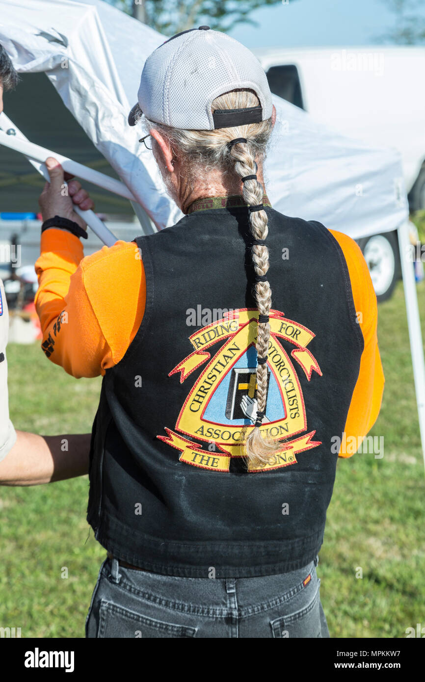 Man with Christian Motorcyclists Association jacket erects canopy at custom car truck and motorcycle show in Gulfport, Mississippi Stock Photo