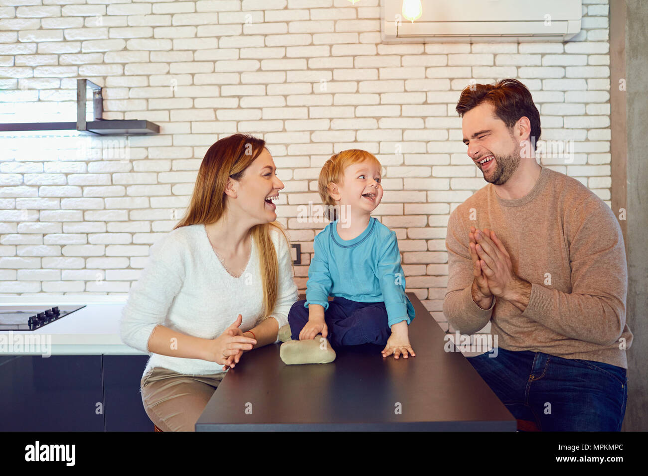 A happy family is playing at the table in the room. Stock Photo