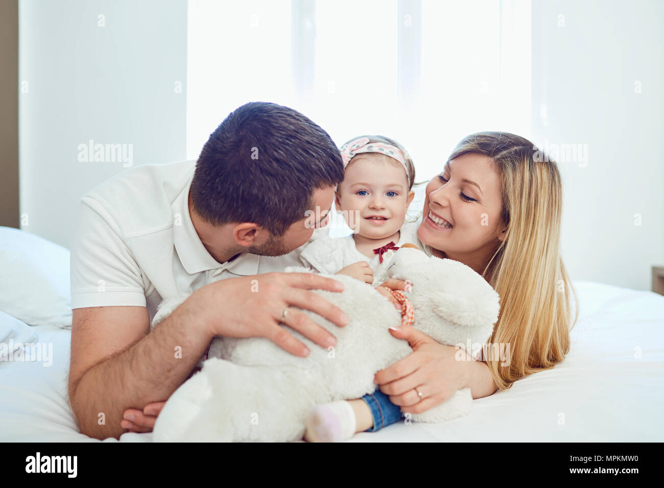 Happy family lying on bed in bedroom Stock Photo