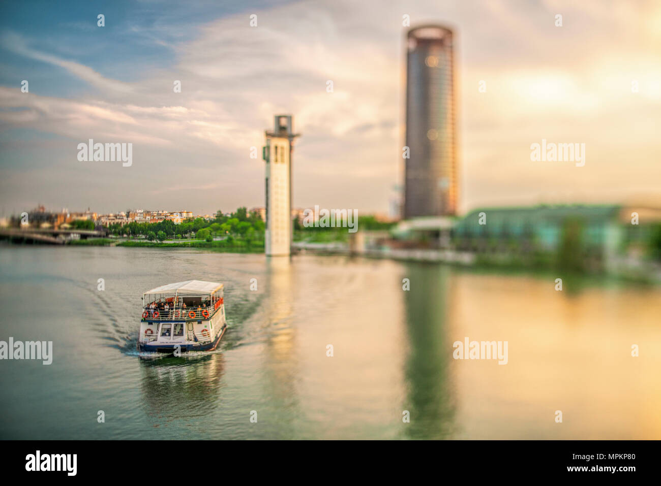 Guadalquivir River Boat Cruise In Seville, Spain. Schlinder and Sevilla Towers on the background. Selective focus through a tilted lens. Stock Photo