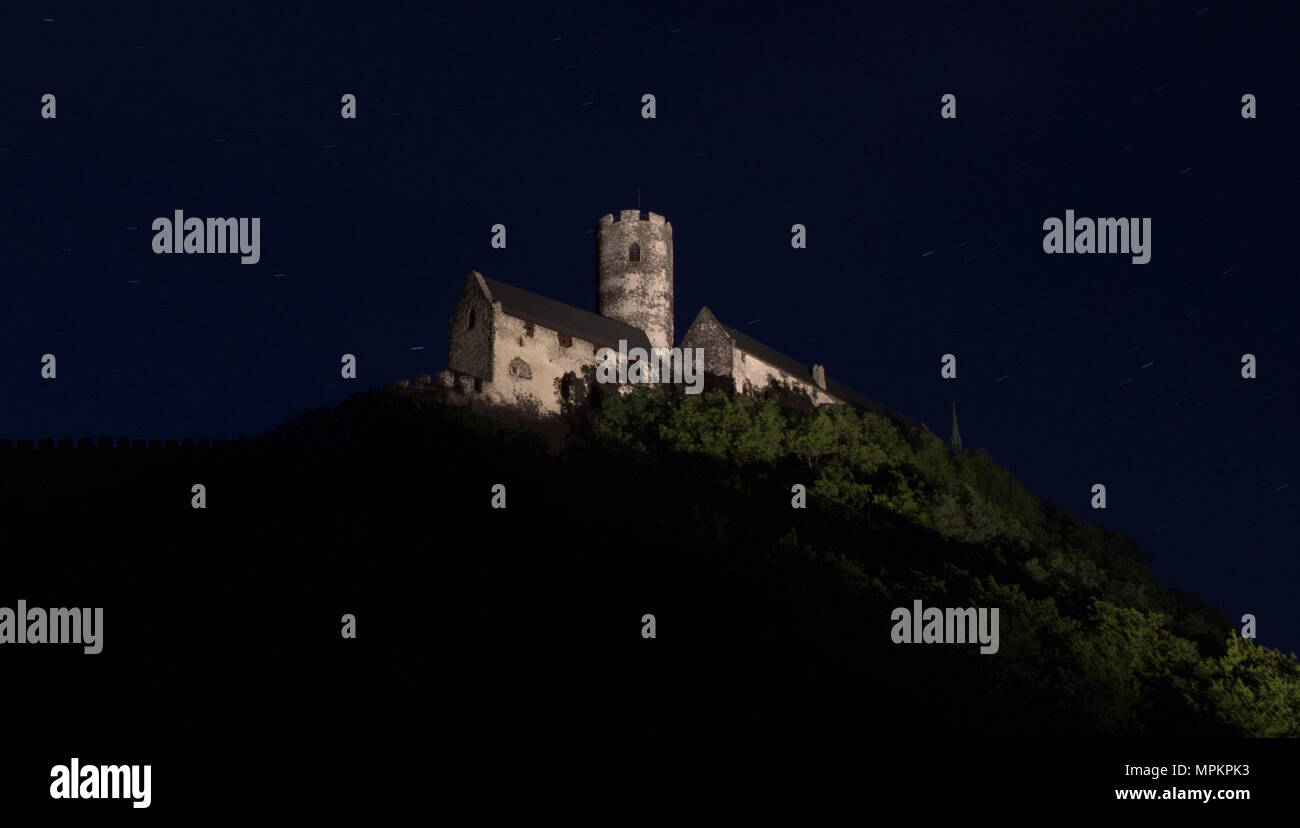 Panoramic view of Bezdez castle in the Czech Republic. In the foreground there are trees, in the background is a hill with castle in the night and sta Stock Photo