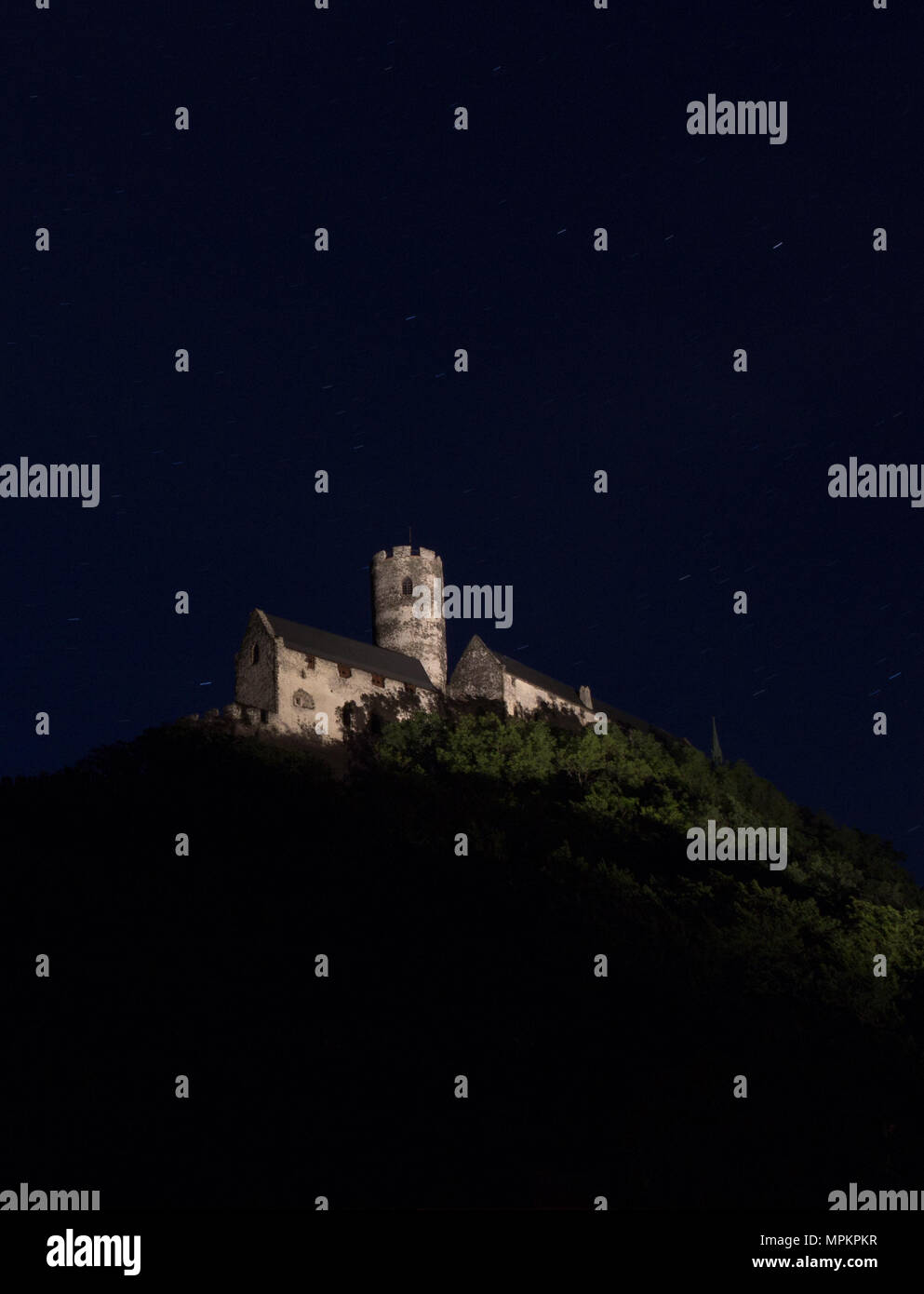 Panoramic view of Bezdez castle in the Czech Republic. In the foreground there are trees, in the background is a hill with castle in the night. Stock Photo