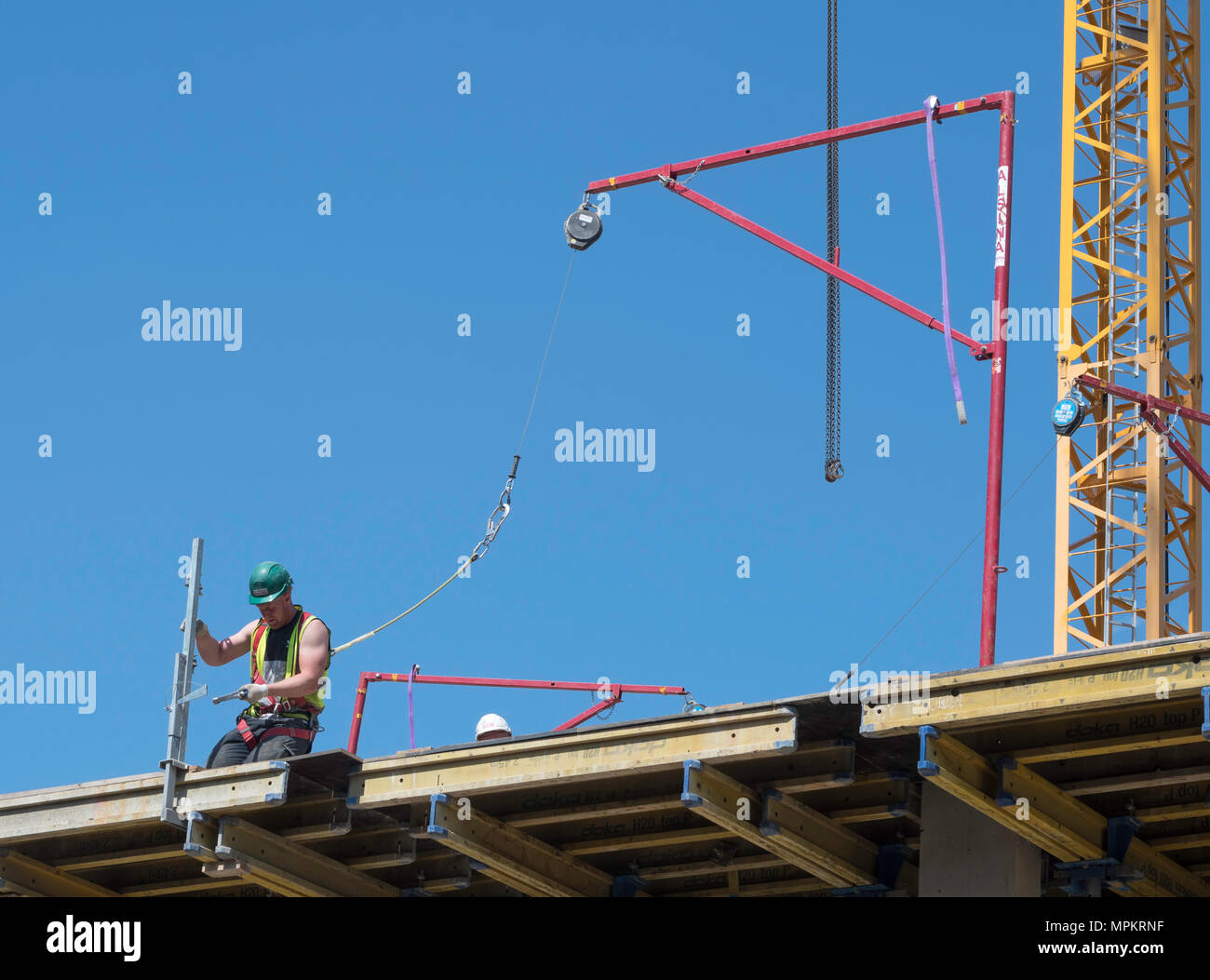 A building construction worker wearing a safety harness attached to an