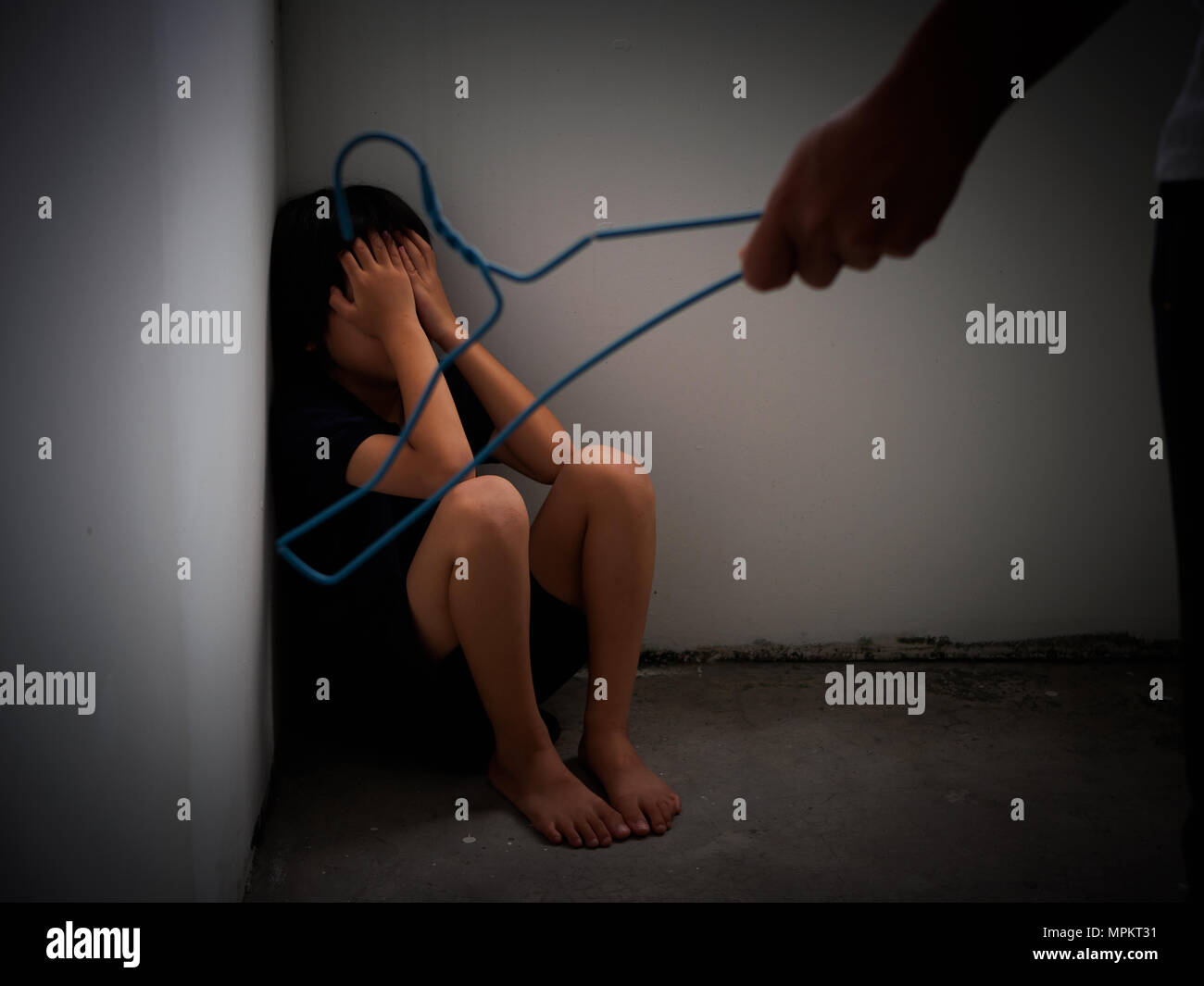 Domestic violence: female hand with Hanger on the background of kid. Abused child, aggression in the family. Stock Photo
