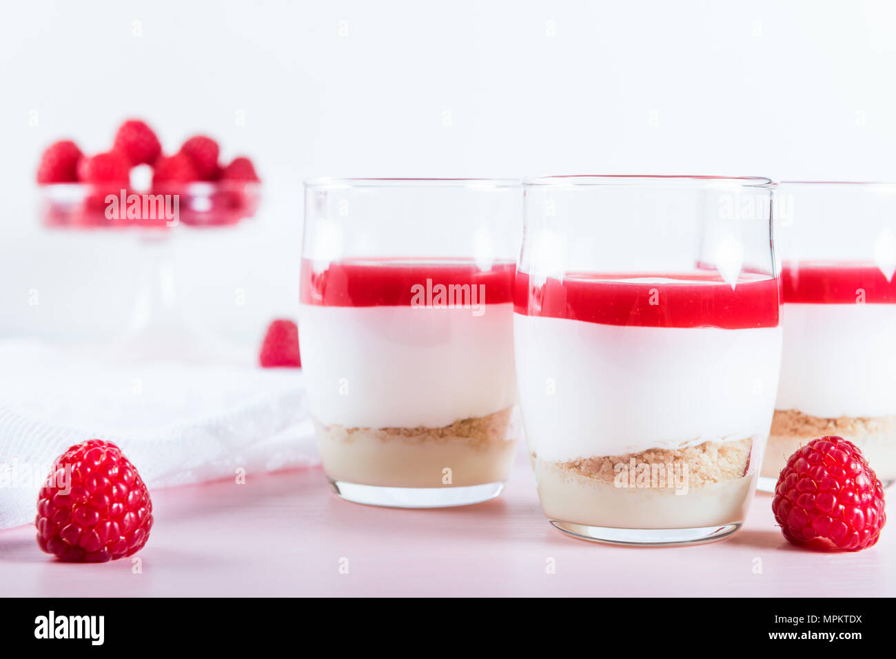 Raspberry dessert from whipped white chocolate mousse, raspberry puree as jelly, and base from almond cookies, light background Stock Photo
