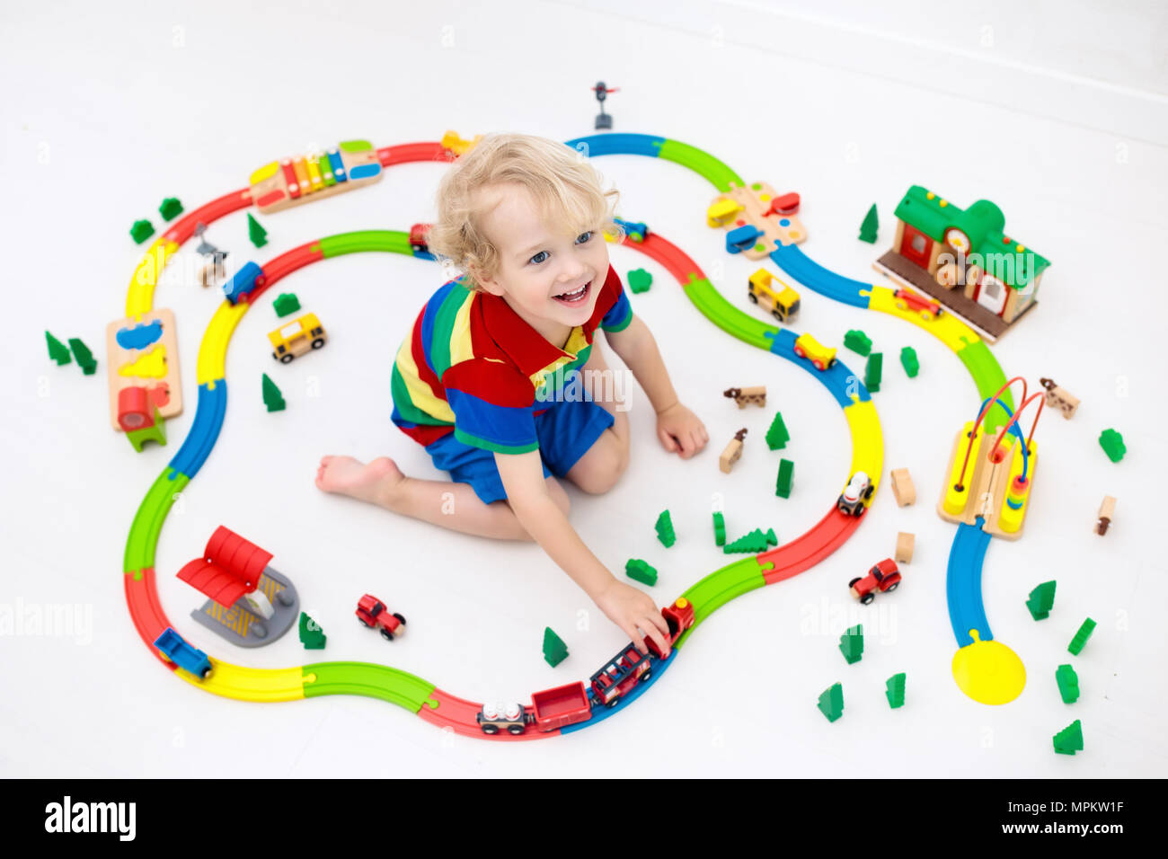 Kids play with toy train railway. Child playing with colorful rainbow