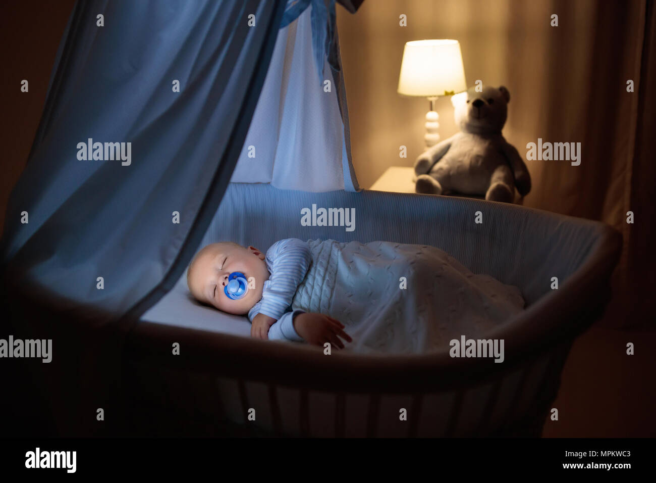 Adorable baby with pacifier sleeping in blue with canopy at