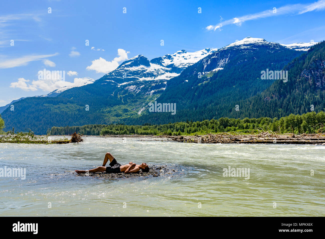 Man relaxing in shallows, Elaho river, near Squamish, British Columbia