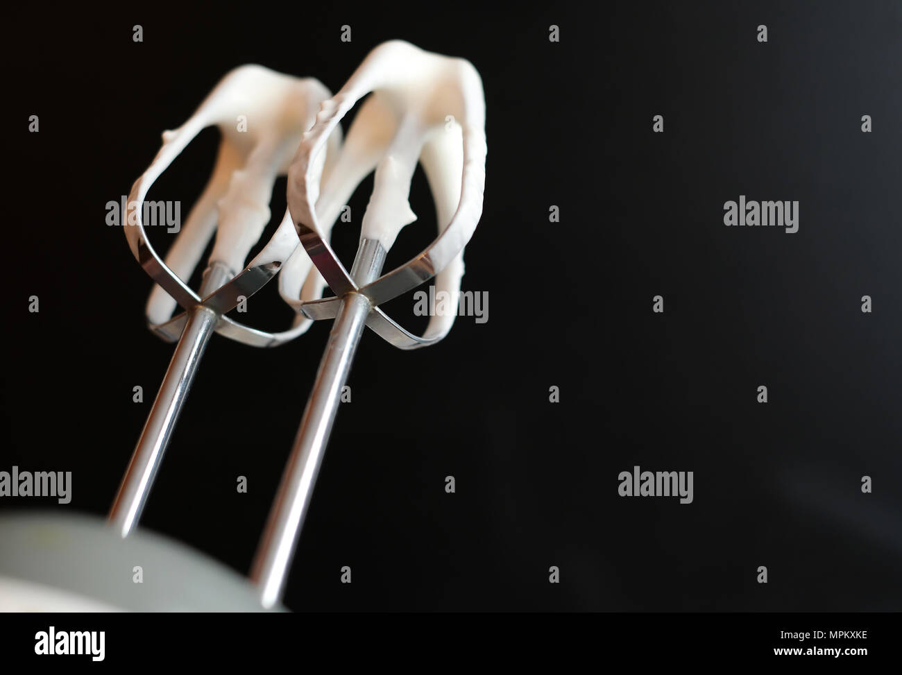 Electric hand mixer with whipped cream on the whisk or beater on a