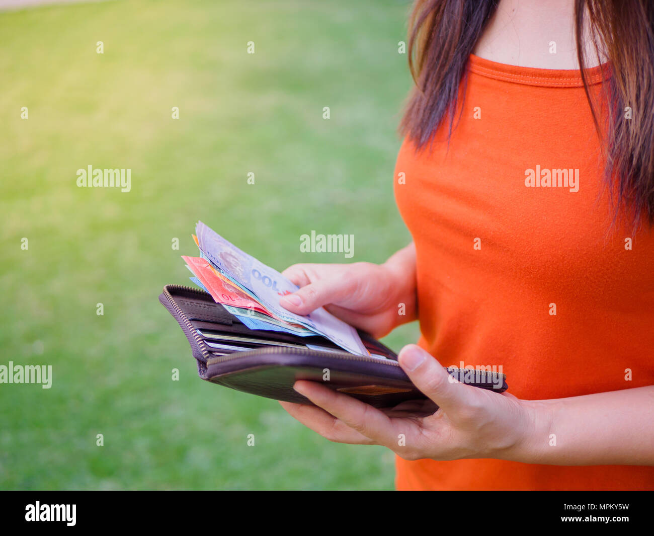 Women Hands taking out money malaysia ringgit from wallet on the green grass field Stock Photo