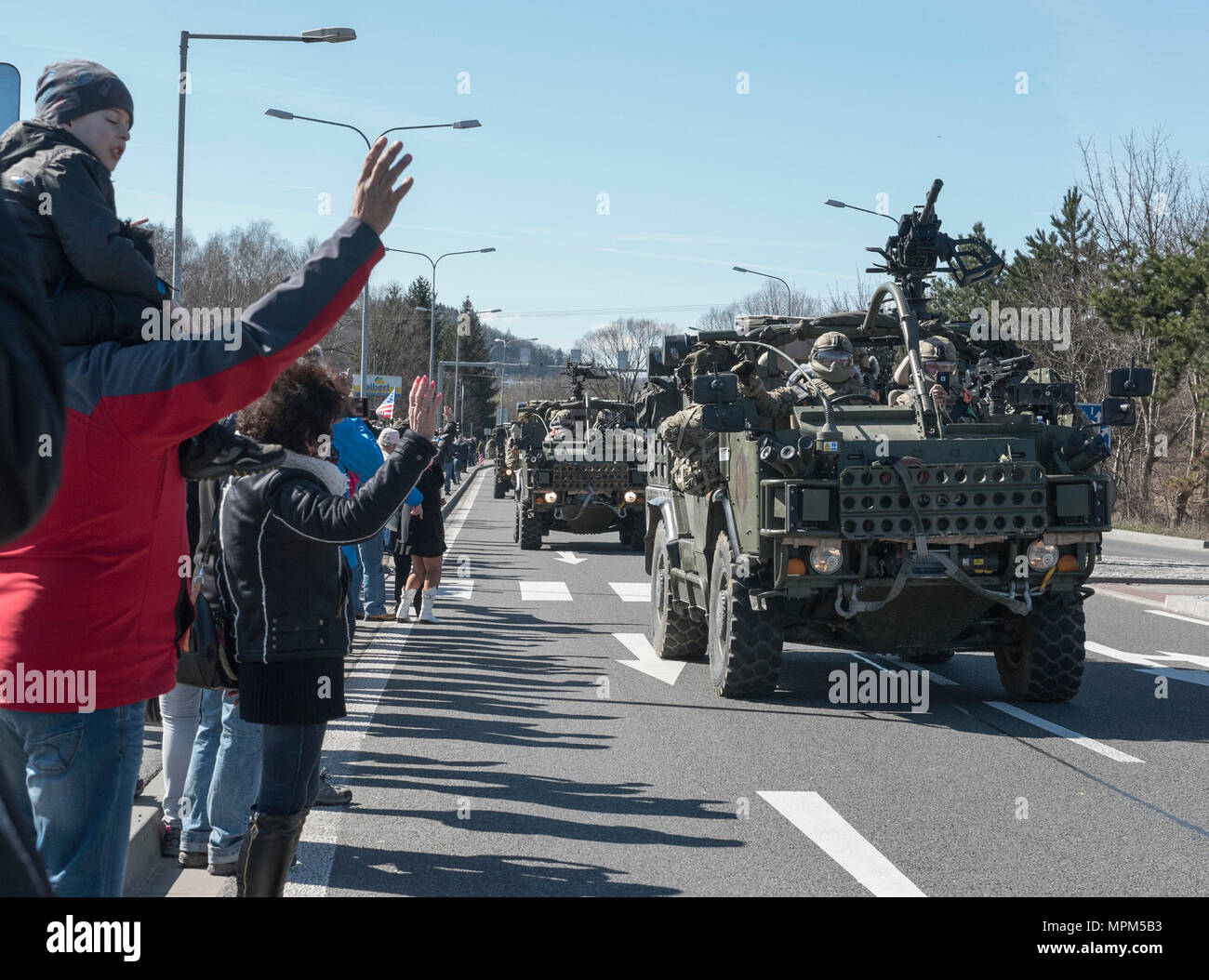 Polish citizens greet the Soldiers of Battle Group Poland as the convoy of tactical vehicles crosses the border from the Czech Republic into Poland March 26, 2017. The contingency of U.S., United Kingdom and Romanian Soldiers convoyed to Orzysz, Poland where they will integrate with the Polish 15th Mechanized Brigade, 16th Infantry Division. The U.S. Army 2nd Squadron, 2nd Cavalry Regiment and other Troop Contributing Nations making up Battle Group Poland will deploy to Poland as part of NATO's Enhanced Forward Presence to serve as a deterrence force. The unique formation is designed to demons Stock Photo