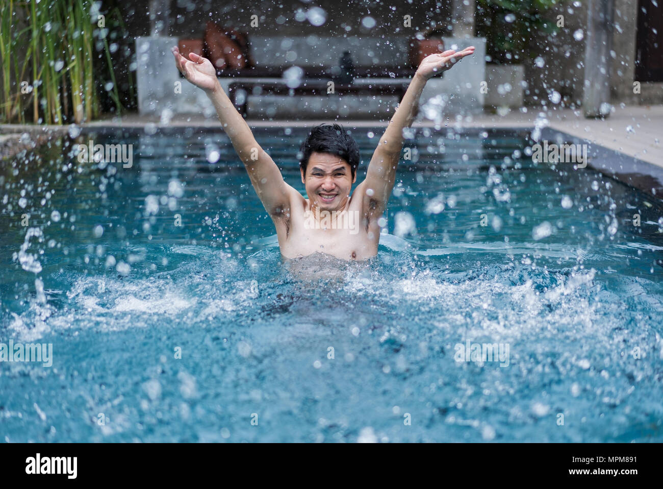 young man in swimming pool and playing water splash Stock Photo