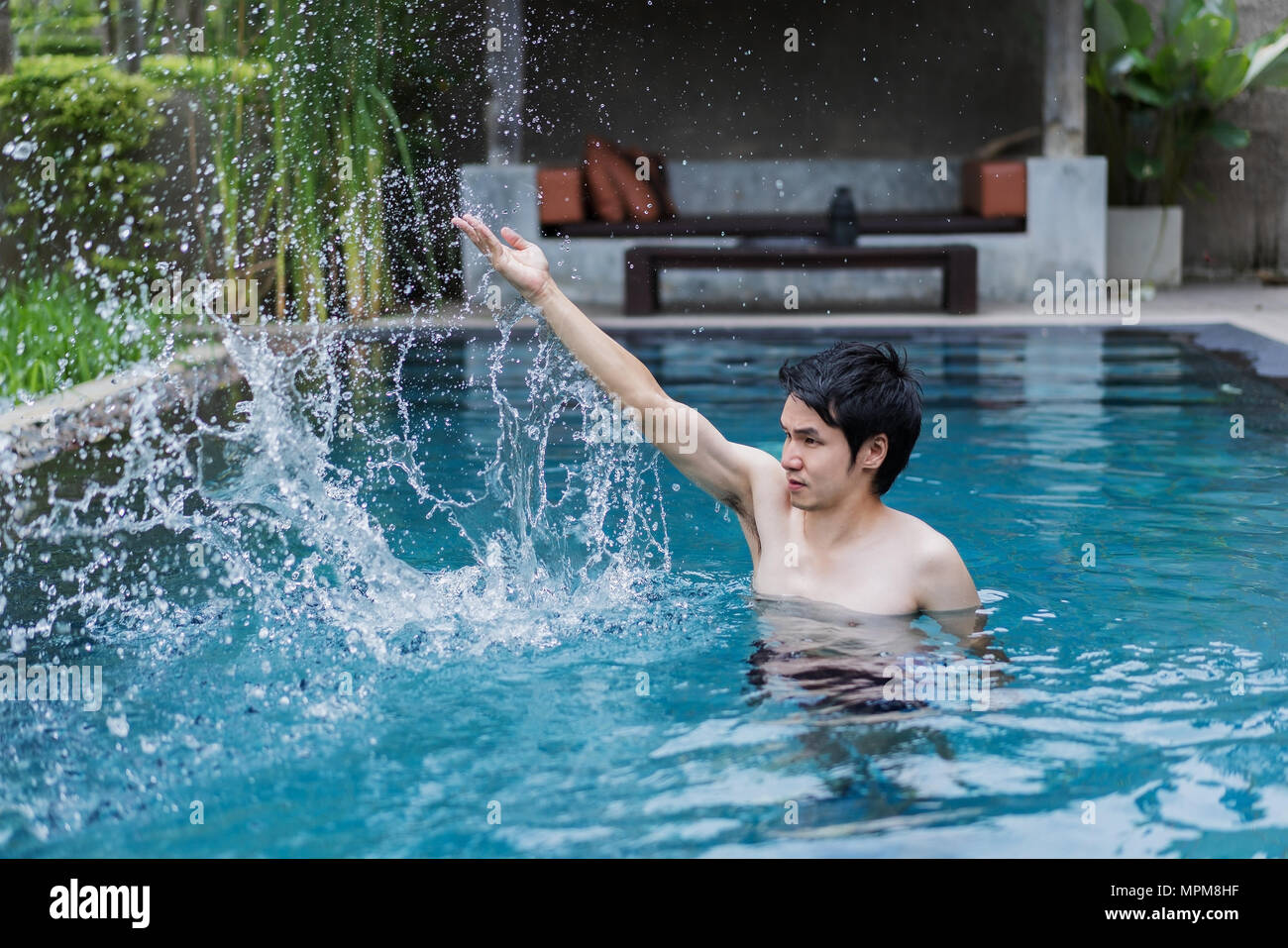 young man in swimming pool and playing water splash Stock Photo