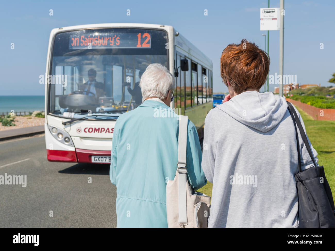 Women catching a single decker number 12 Compass bus in Rustington, West Sussex, England, UK. Stock Photo