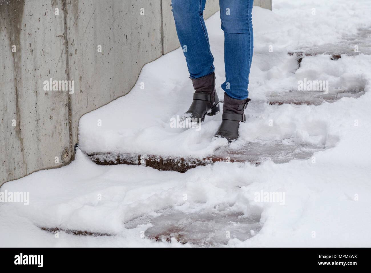 Female legs wearing boots going down the stairs on snowy pathway at winter. Stock Photo