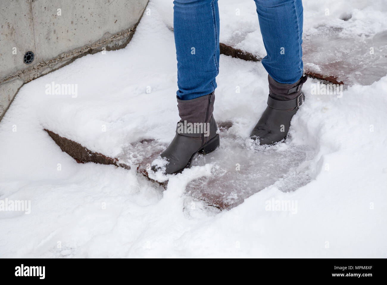 Female legs wearing boots walking down the stairs on snowy pathway at winter. Stock Photo