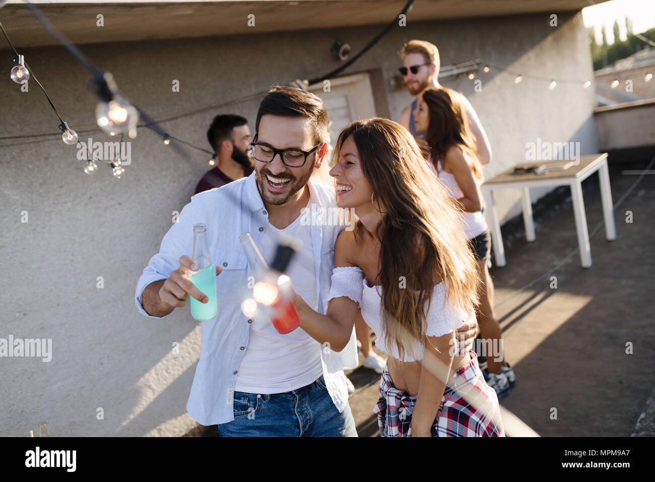 Happy young couple drinking cocktail on rooftop Stock Photo