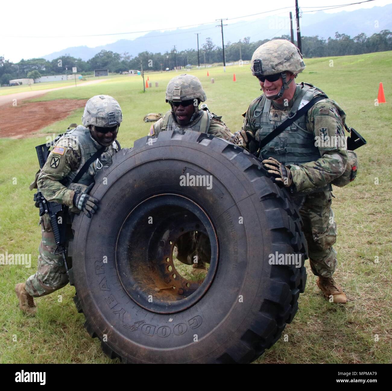 Sgt. Shannon Leftwich, Sgt. Todd Kelly and Sgt. Dylon Dibble, from the 95th Engineer Company (Sapper), 84th Engineer Battalion, flip a 400 pound Heavy Expanded Mobility Tactical Truck tire (HEMTT) during the 'Never Daunted' Best Squad Competition. Stock Photo