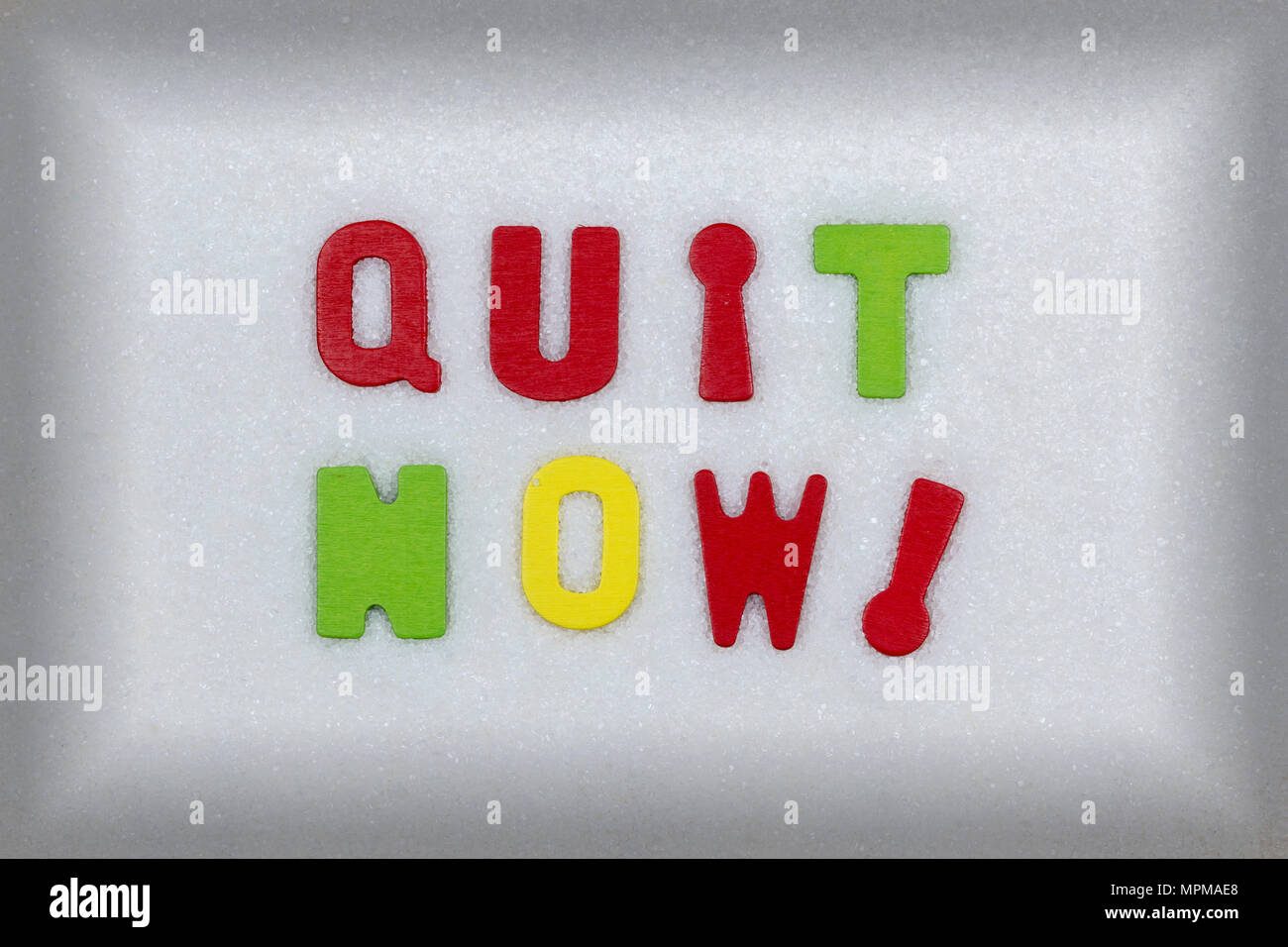 "Quit now!" in colorful wooden letters atop a white sugar crystal background, health risks of ...