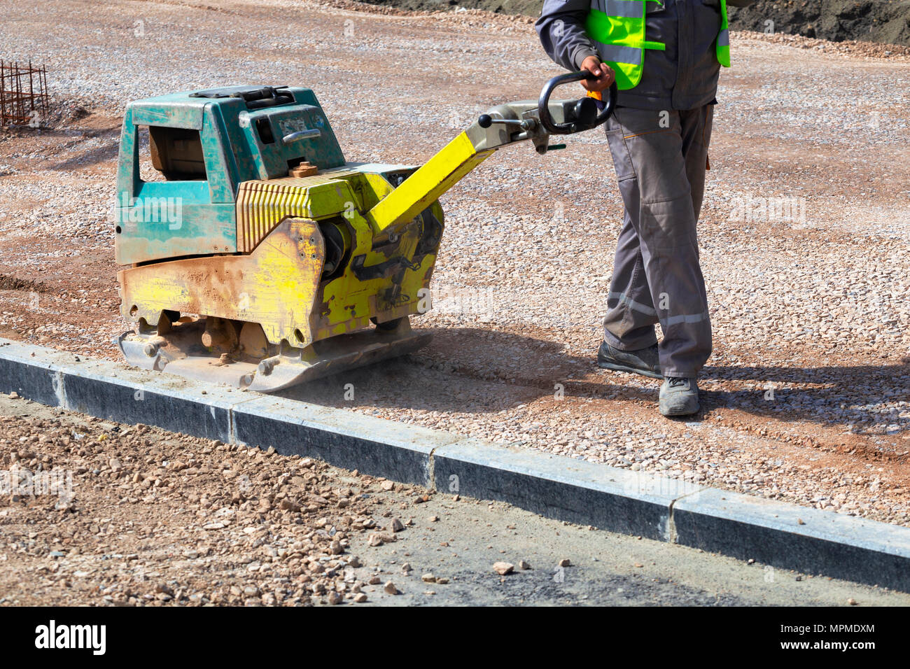 Worker compacting soil using compactor in a city park, pavement  reconstruction Stock Photo - Alamy