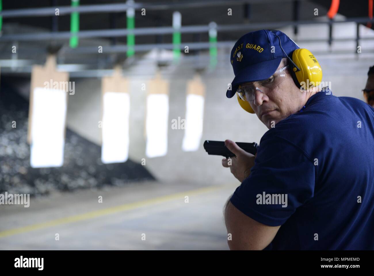 Petty Officer 2nd Class Jason Desrosiers, a maritime enforcement specialist at Coast Guard Sector Honolulu, visually scans his surroundings while conducting a live fire exercise during a Firearms Training and Evaluation – Pistol course at the Dexter Small Arms Firing Range at Base Honolulu, March 28, 2017. The FT&E-P, which will replace the Basic Pistol Marksmanship Course, will qualify Coast Guard law enforcement personnel using a four-phased approach of training, practice, qualification and proficiency. (U.S. Coast Guard photo by Petty Officer 2nd Class Tara Molle/Released) Stock Photo