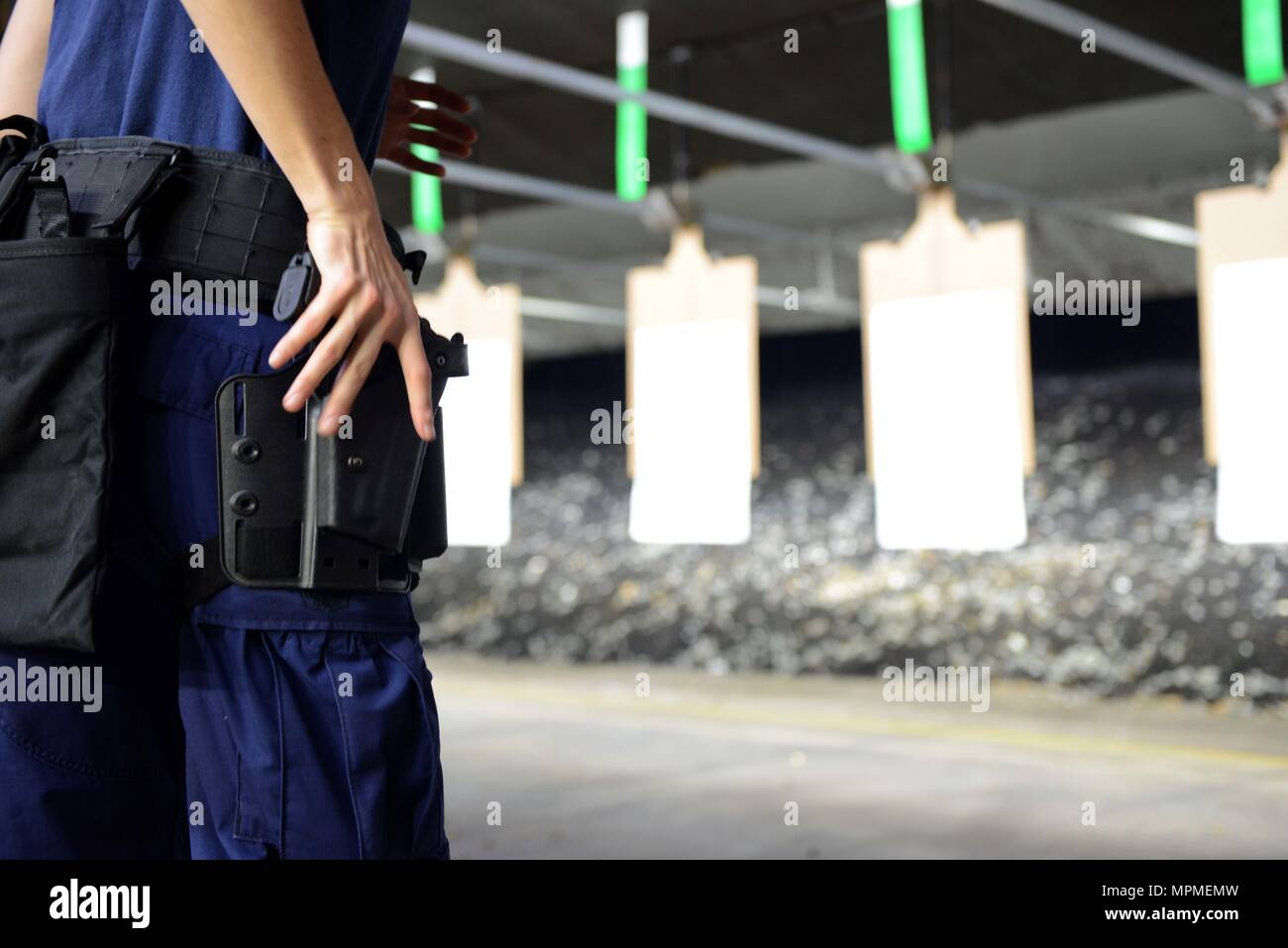 A Coast Guard crewmember prepares to draw their weapon during a live