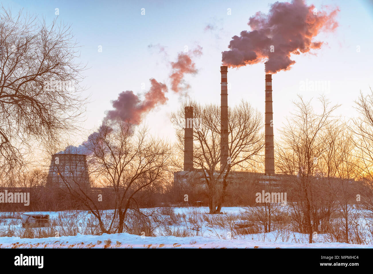 The smokestacks of an industrial plant at sunset. Environmental pollution Stock Photo