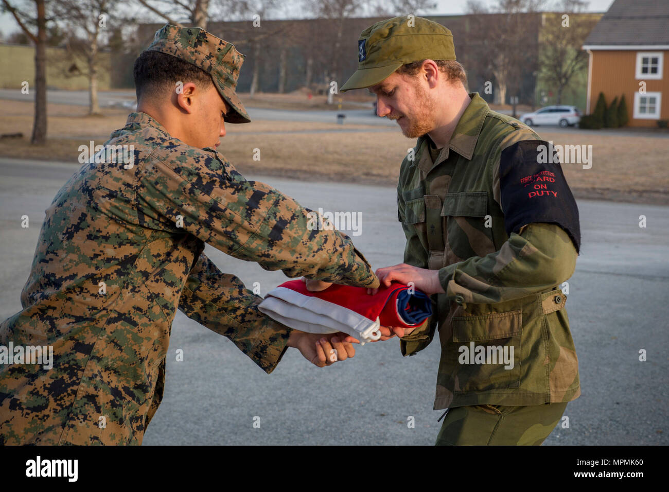 U.S. Marine Lance Cpl. Austin Robinson, a warehouse clerk with Marine Rotational Force Europe (MRF-E) 17.1, hands off the Norwegian flag at Vaernes Garnison, March 30, 2017. MRF-E uphold traditions while increasing interoperability with Allies and partner nations. (U.S. Marine Corps photo by Lance Cpl. Victoria Ross) Stock Photo