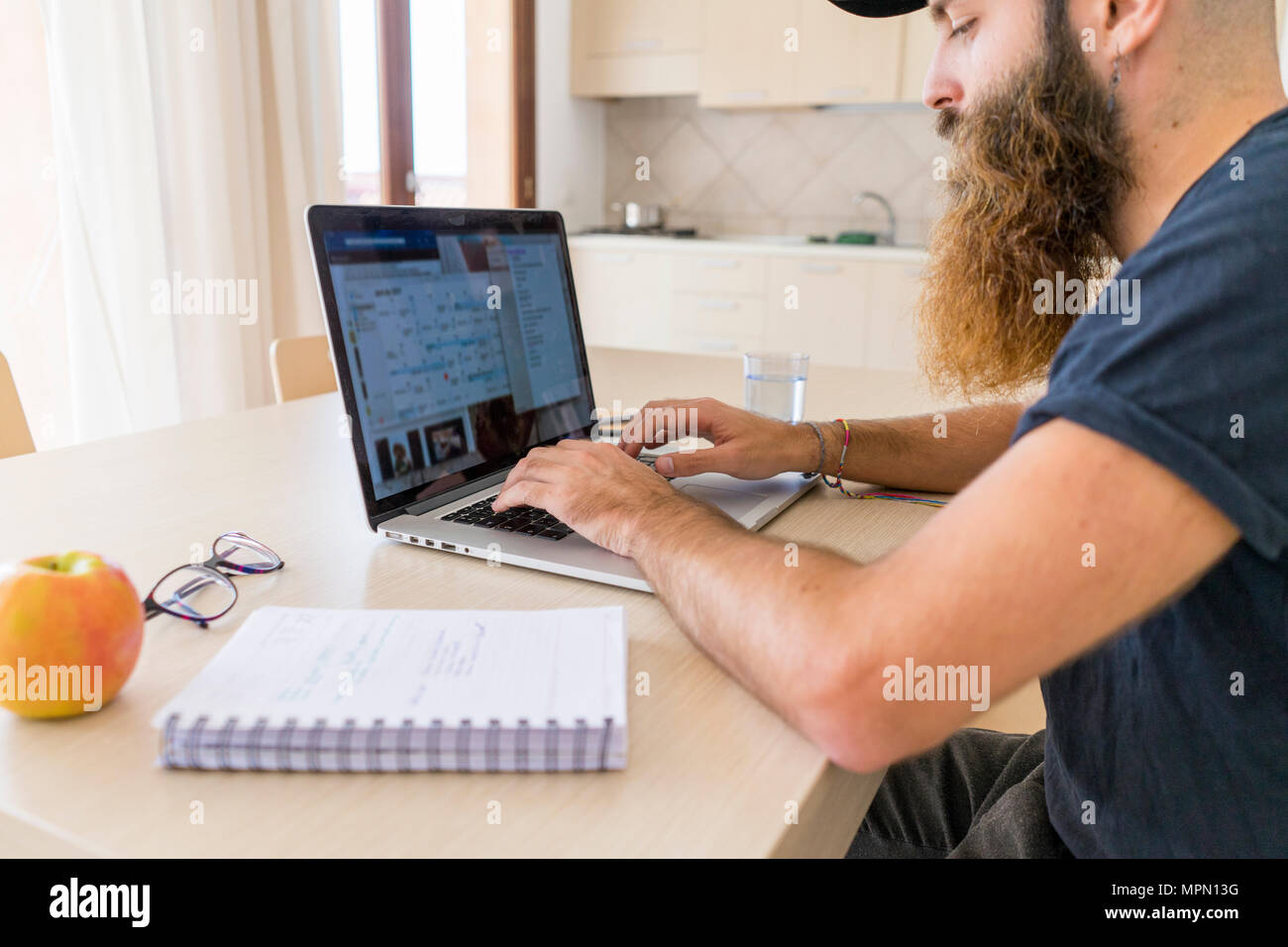 Bearded young man working on laptop at home Stock Photo
