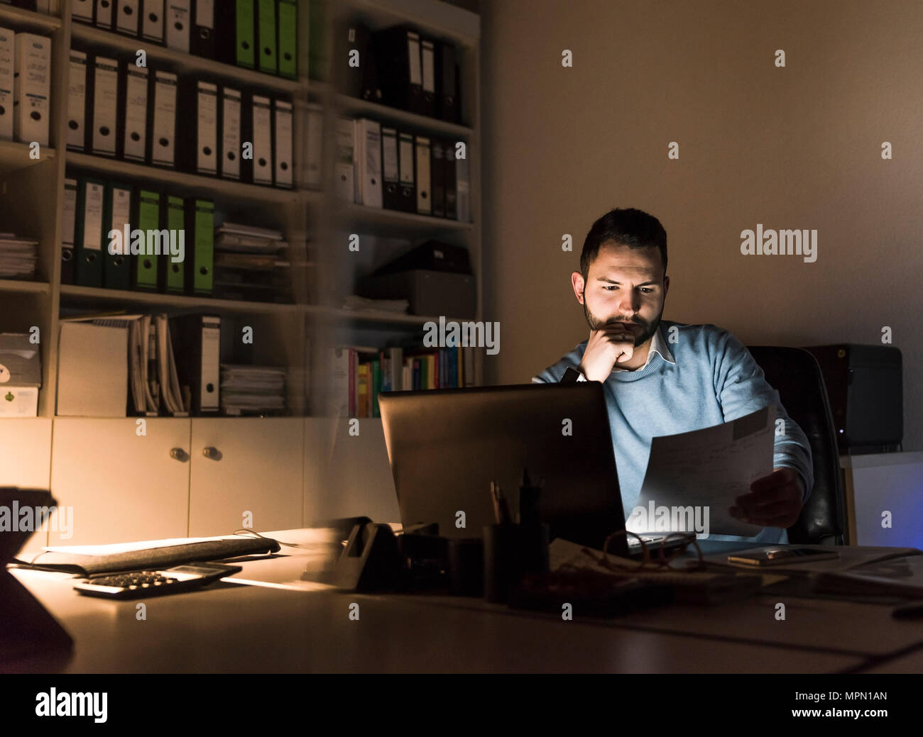 Businessman working at desk in office at night Stock Photo