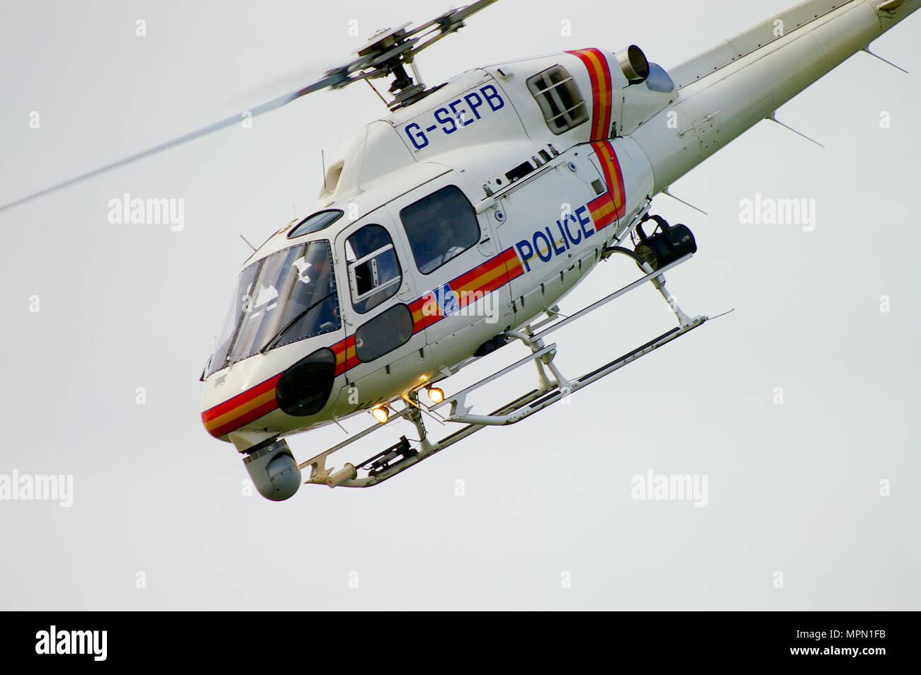 Police helicopter G-SEPB Eurocopter AS355 Ecureuil (Squirrel) with nose camera sight turret. Flying Stock Photo