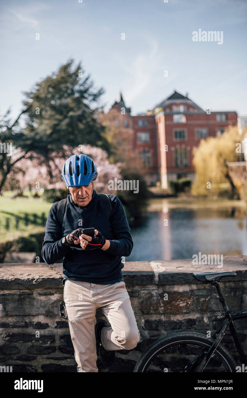 Senior man with cycling helmet using smartphone Stock Photo