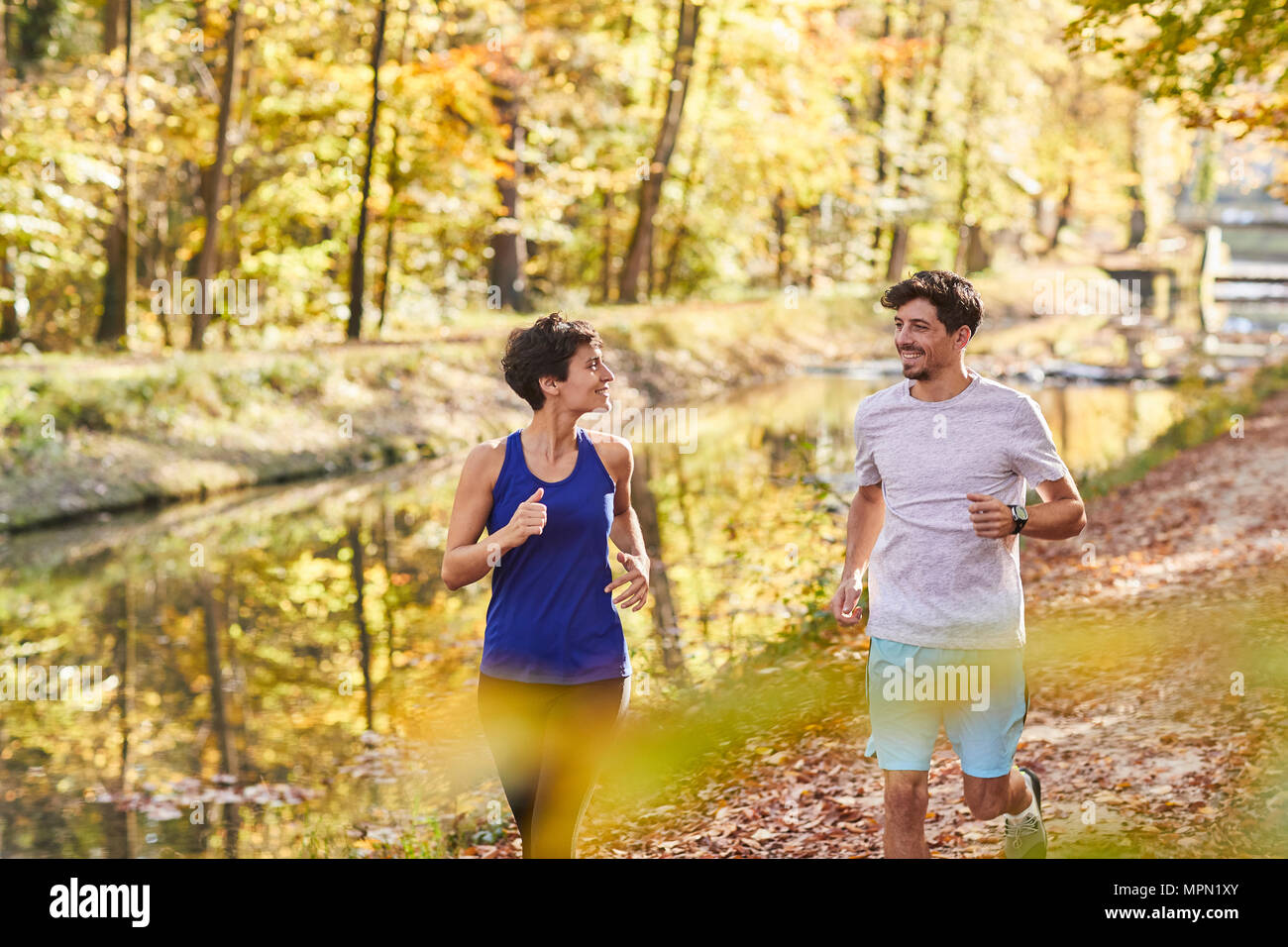 Couple jogging on autumnally forest track Stock Photo