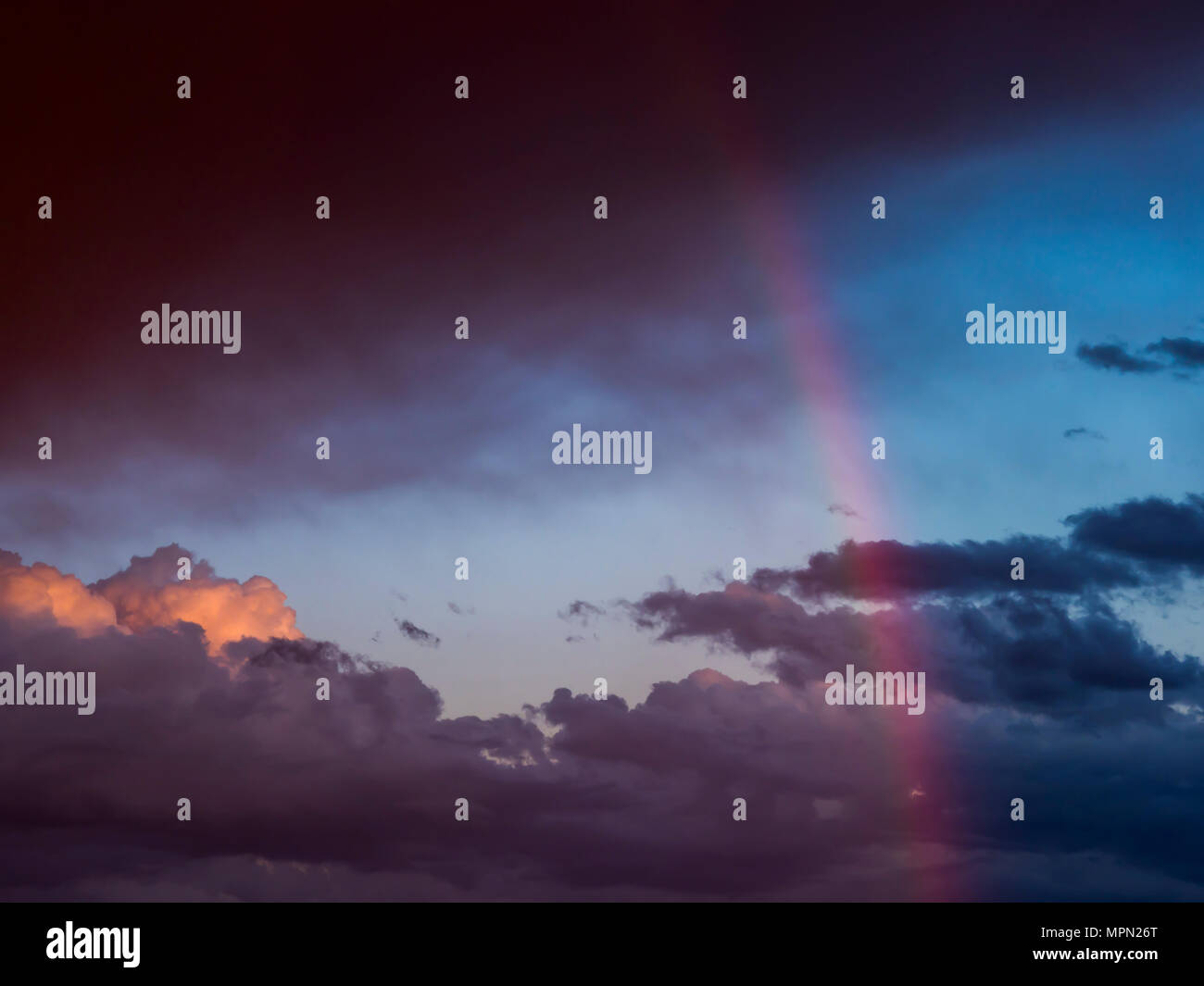 Austria, Hoersching, dark clouds after thunderstorm and rainbow Stock Photo