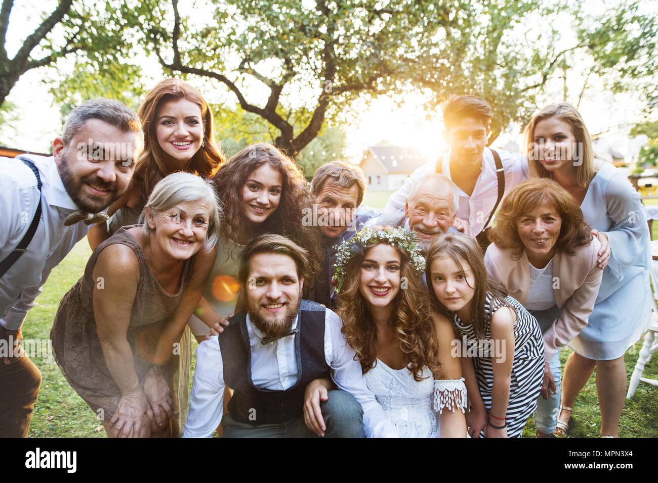 Bride, groom, guests posing for the photo at wedding reception outside