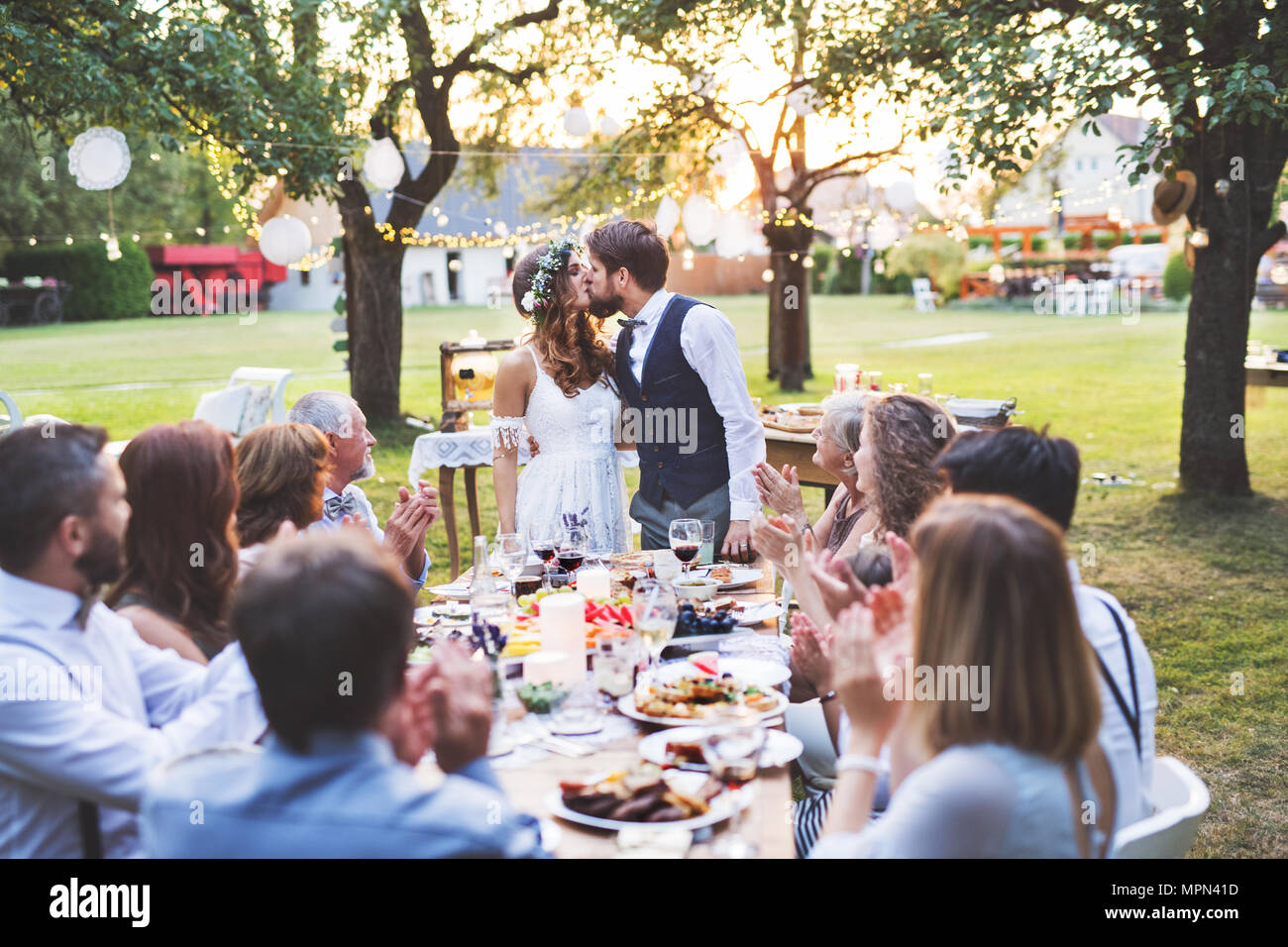 Bride and groom with guests at wedding reception outside in the backyard. Stock Photo