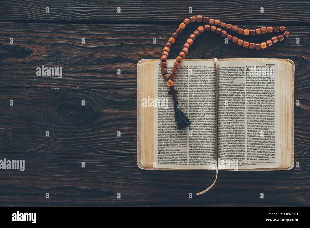 top view of open holy bible with rosary on wooden table Stock Photo
