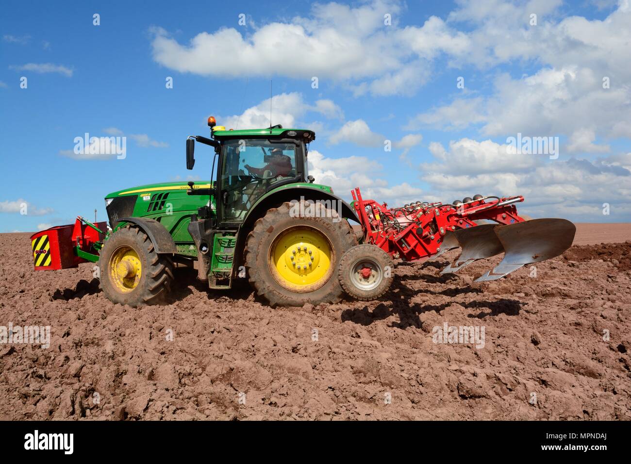 man using tractor and ridging machine to prepare furrows for Pembrokeshire potatoes Wales Cymru UK Stock Photo