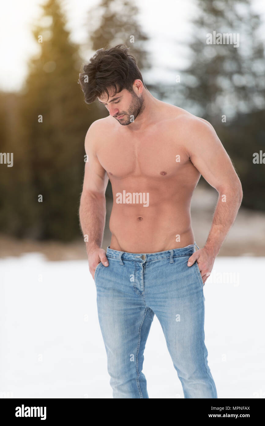 Healthy Young Man Standing Strong Flexing Muscles While Wearing Blue Jeans - Muscular Athletic Bodybuilder Fitness Model Posing Outdoors - a Place for Stock Photo