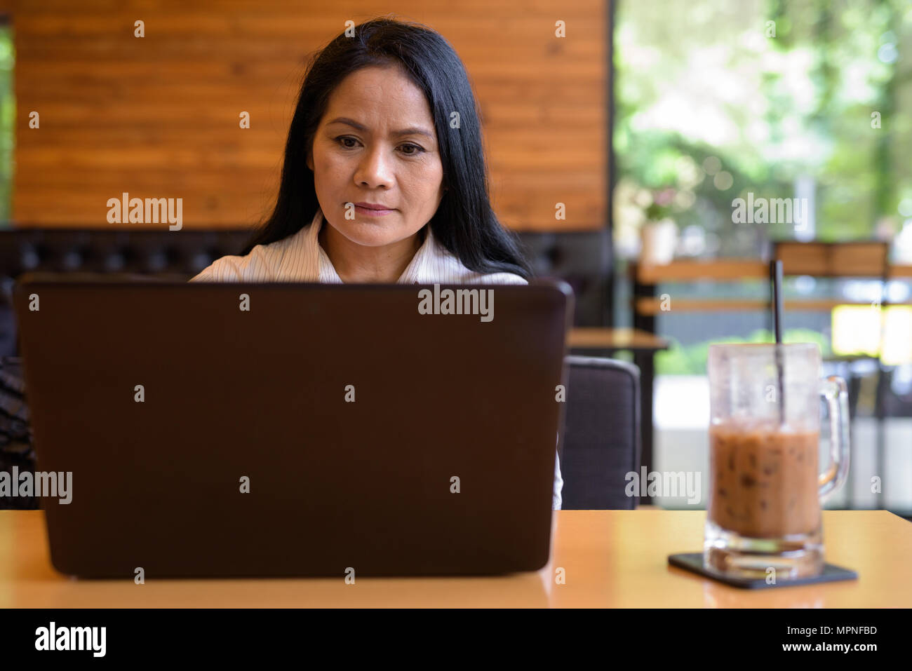 Mature Asian businesswoman relaxing at coffee shop Stock Photo