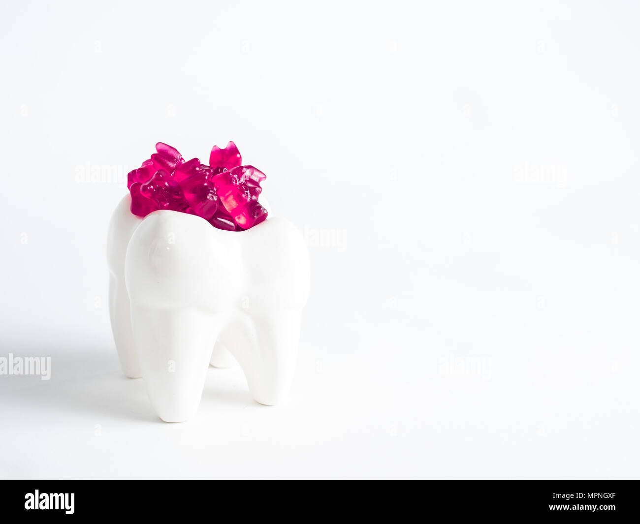 The porcelain tooth is filled with gummy bears against a white background Stock Photo