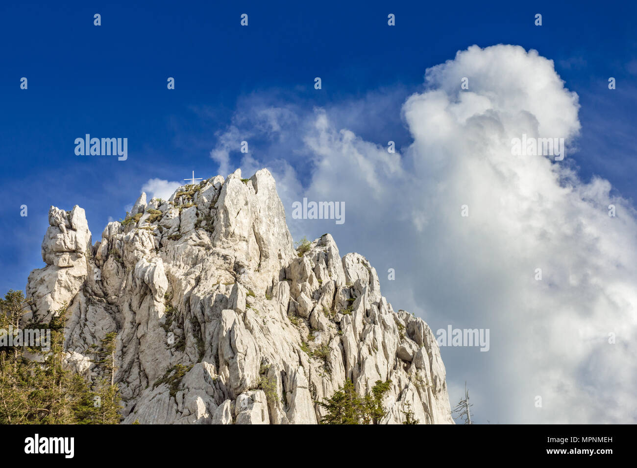 Mountain top with summit cross, with clouds building up in the background. Taken along Via Dinarica, in strict nature reserve Bijele stijene, Croatia. Stock Photo