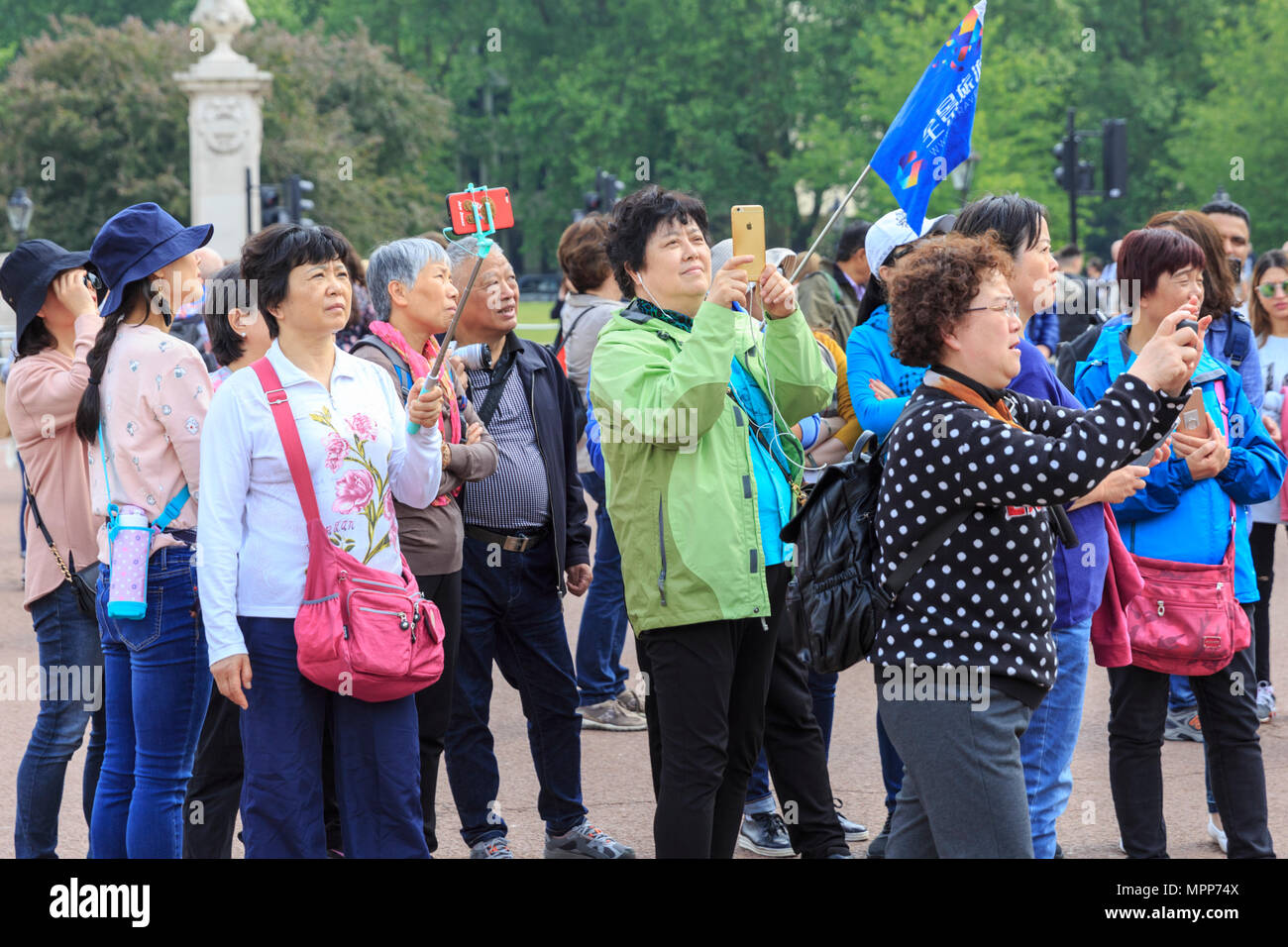 Buckingham Palace, London, 24th May 2018. An Asian tour group takes pictures of people going into the Palace. People queuing to enter the Palace for the The Duke of Edinburgh's Awards mix with curious tourists and Londoners enjoying the afternoon sunshine at Buckingham Palace. The Awards are a youth awards programme founded in the United Kingdom in 1956 by Prince Philip, Duke of Edinburgh. Credit: Imageplotter News and Sports/Alamy Live News Stock Photo