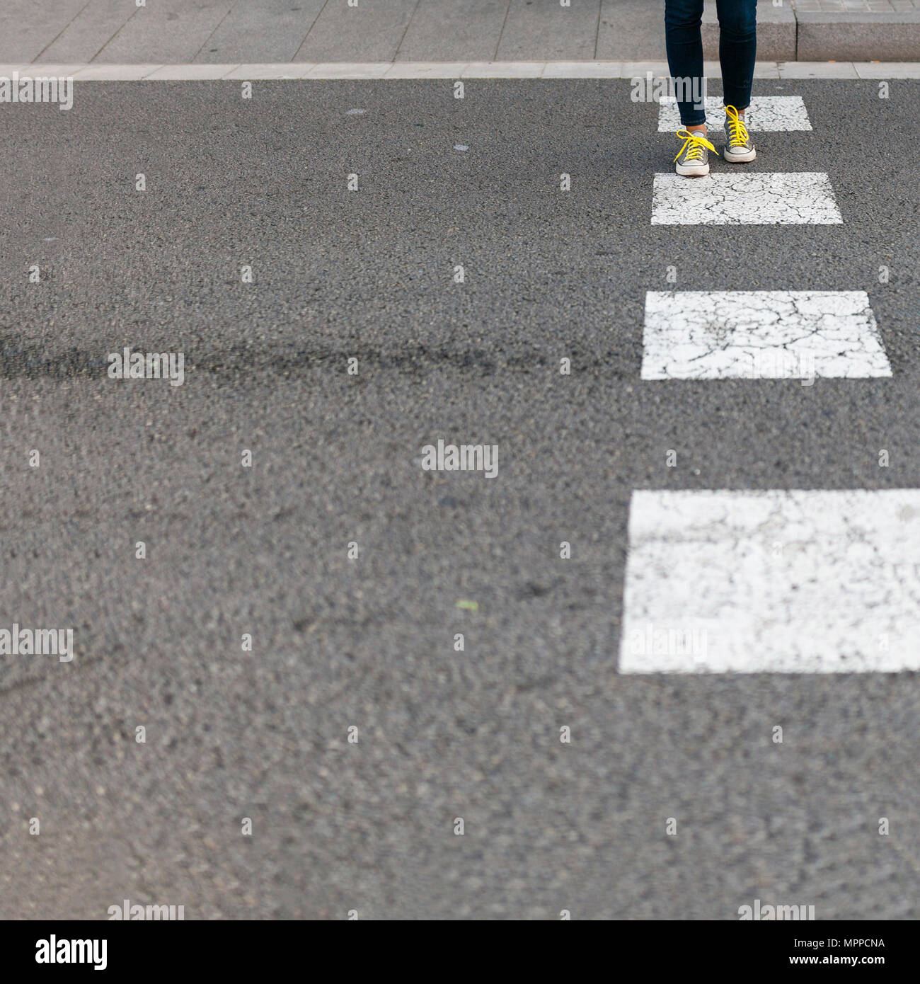 Close-up of woman wearing sneakers crossing street Stock Photo