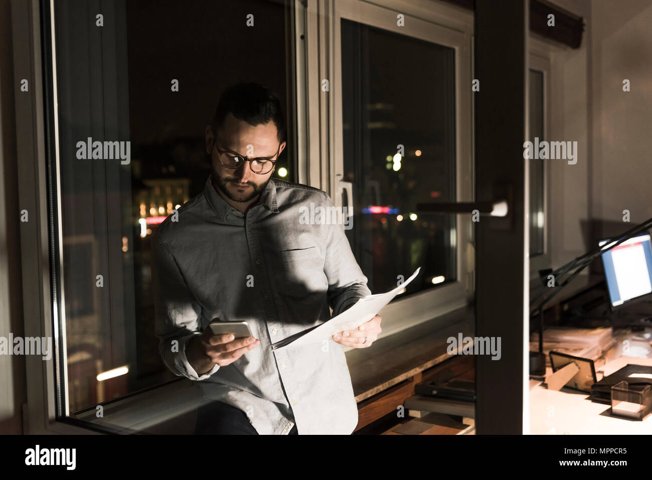 Businessman in office at night using smartphone Stock Photo