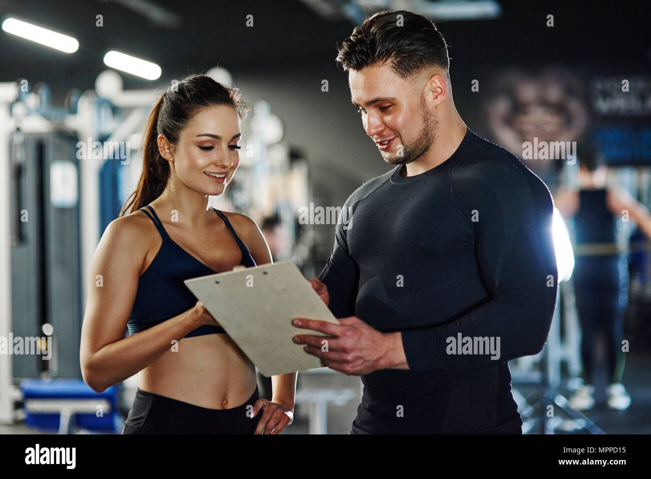 Personal trainer talking to woman in gym Stock Photo