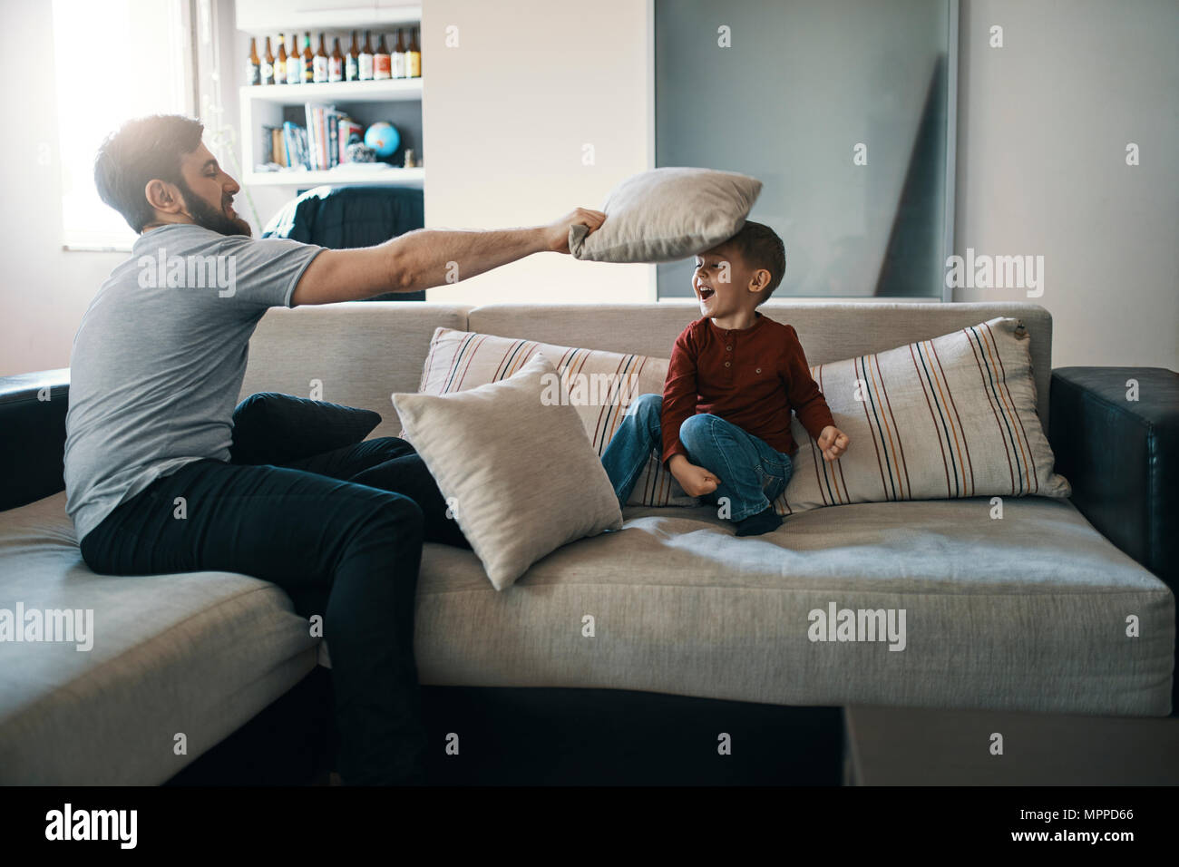 Father And Little Son Playing Together On The Couch In The