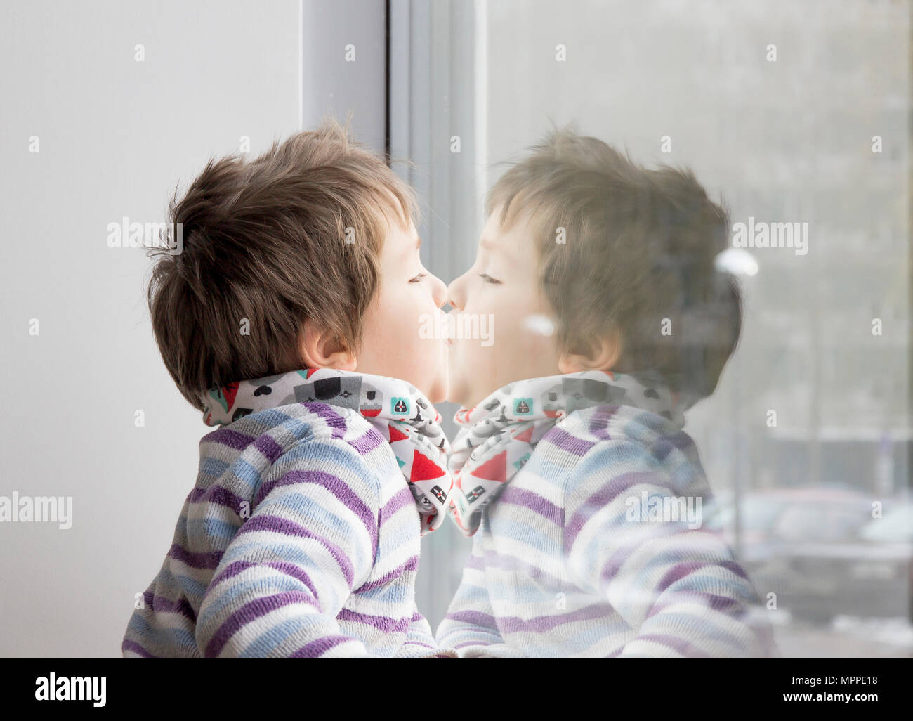 Little boy leaning face to window Stock Photo